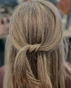 Close-up of the back of a person's head with straight, light brown hair styled in a loose, simple knot—showcasing the smooth finish of a Brazilian Blowout Anastasia Island. - Get Panache, FL