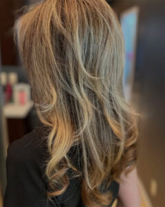 Woman with shoulder-length, wavy blonde hair featuring highlights, photographed from behind in an indoor setting at a luxury deep tissue massage St. Augustine spa. - Get Panache, FL