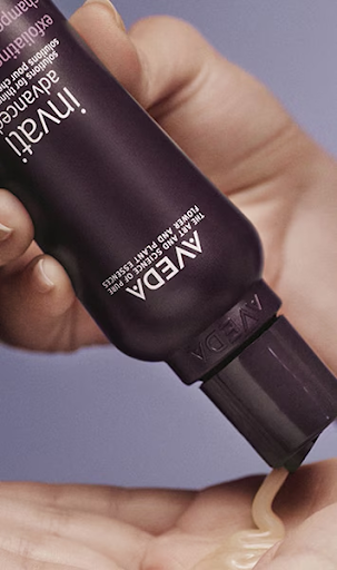 A hand squeezes a tube of AVEDA Invati Advanced Exfoliating Shampoo, dispensing the product onto the palm. - Get Panache, FL
