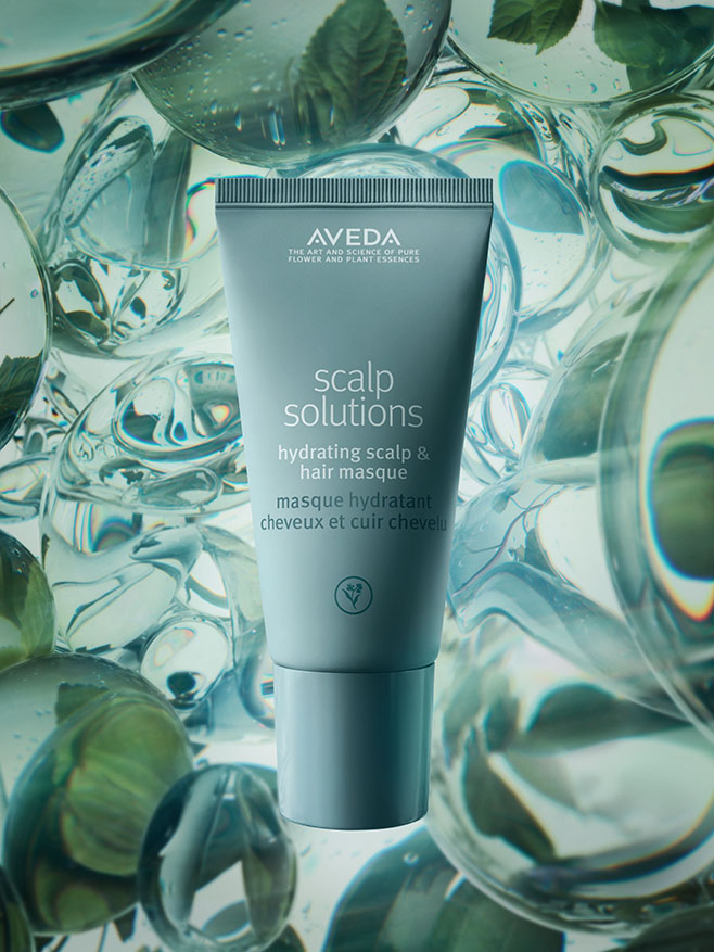 Aveda Scalp Solutions Hydrating Scalp & Hair Masque tube stands upright, surrounded by clear liquid bubbles and floating mint leaves. - Get Panache, FL